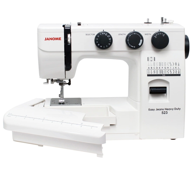 Maszyna do szycia Janome HD 523 EASY JEANS w kolorze białym, z pokrętłami do wyboru ściegów, długości i szerokości. Widoczny stół roboczy z oznaczeniami centymetrowymi. Z przodu instrukcje dotyczące różnych ściegów oraz logo Easy Jeans Heavy Duty 523.