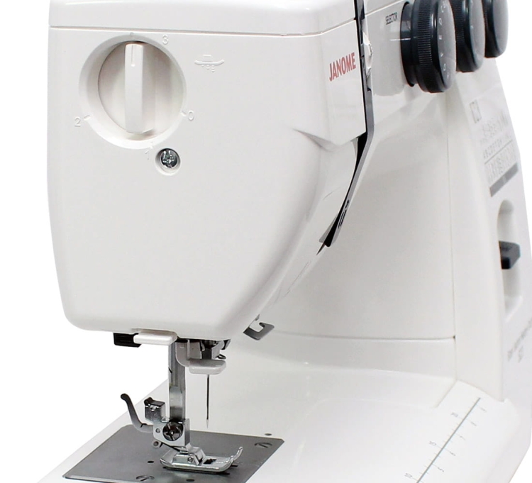 Maszyna do szycia Janome HD 523 EASY JEANS w białej obudowie. Widoczny mechanizm nawlekania, stopka do szycia oraz pokrętła regulacyjne. Ujęcie z boku, ukazujące detal szycia i podstawę maszyny.
