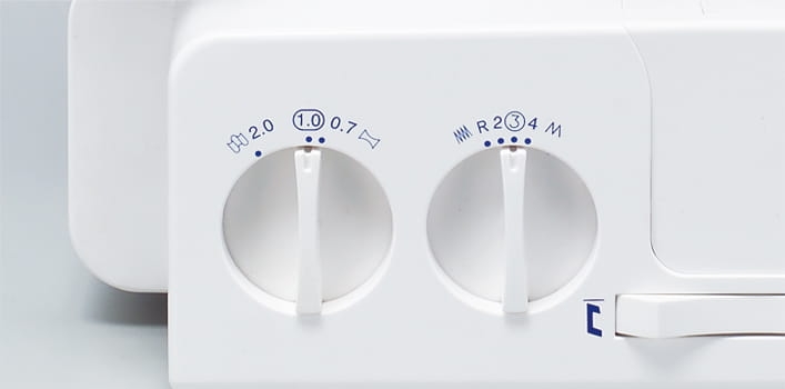 Panel sterujący owerloka Minerva M840DS z dwoma pokrętłami do regulacji: lewe z oznaczeniem 2.0 i 1.0, prawe z numerami 1, 2, 3, 4 oraz oznaczeniem R. Biały kolor obudowy, minimalistyczny design, widoczna dźwignia do ustawień.