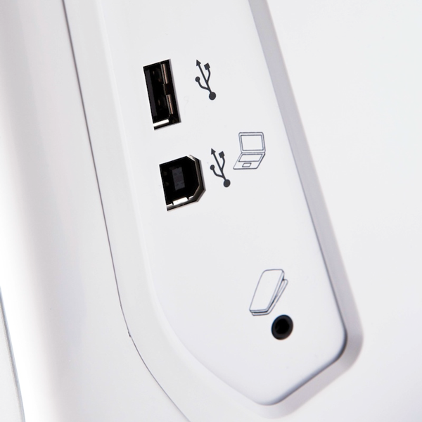 Widok z bliska na panel boczny maszyno-hafciarki Brother Innov-is V5 LE. Widoczne dwa porty USB, ikony przedstawiające połączenie z komputerem oraz zasilanie. Tło białe, panel w kolorze białym z delikatnym wykończeniem.
