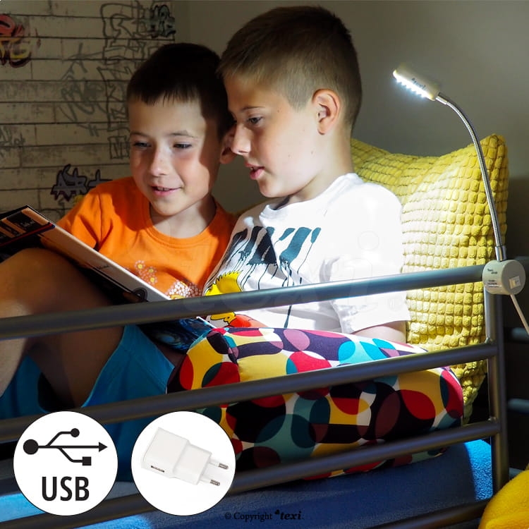 Lampka do maszyn szwalniczych TEXI LED USB, z 12 diodami LED, umieszczona na metalowym ramieniu, świeci na jasno, ułatwiając czytanie. W tle widoczni chłopcy siedzący na łóżku, otoczeni kolorowymi poduszkami. Złącze USB widoczne w dolnym rogu.
