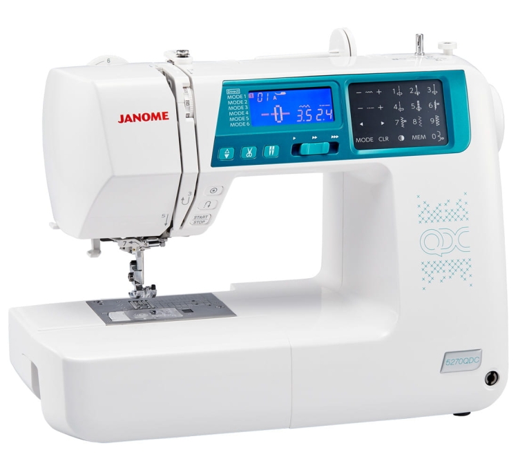 Maszyna do szycia Janome 5270QDC w kolorze białym z niebieskimi akcentami, z elektronicznym panelem sterującym, wyświetlaczem LCD i różnymi programami szycia. Ujęcie frontalne, maszyna leżąca na płaskiej powierzchni, z widoczną stopką i igłą.