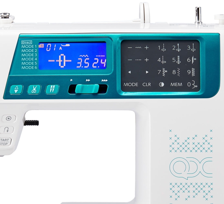Maszyna do szycia Janome 5270QDC z niebieskim wyświetlaczem LCD, przyciskami do wyboru ściegów i ustawień, w białej obudowie. Widoczne oznaczenia trybów szycia oraz logo QDC na bocznej ściance. Ujęcie frontalne.