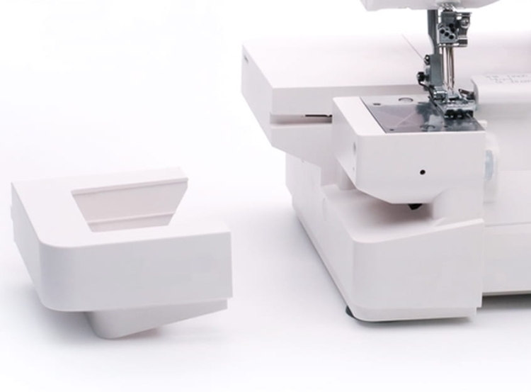 Coverlok Minerva M5000CL to biała overlock z funkcją renderki. Widoczny detal to odłączona część maszyny z prostokątnym otworem. Kąt ujęcia z boku, na białym tle, ukazuje konstrukcję i elementy funkcjonalne.