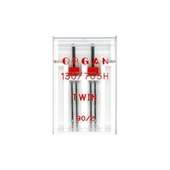 Igła podwójna półpłaska 130/705H Organ TWIN 90/2mm, 2 sztuki w przezroczystym opakowaniu. Widoczne dwa metalowe groty igieł z czerwonymi uchwytami. Na opakowaniu widnieją napisy: ORGAN, TWIN, 130/705H, 90/2.