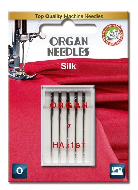 Igły półpłaskie ORGAN HAx1GT do jedwabiu w blistrze, zawierające pięć igieł o numerze 7. Opakowanie na tle czerwonego materiału, z widocznymi napisami ORGAN i Silk.