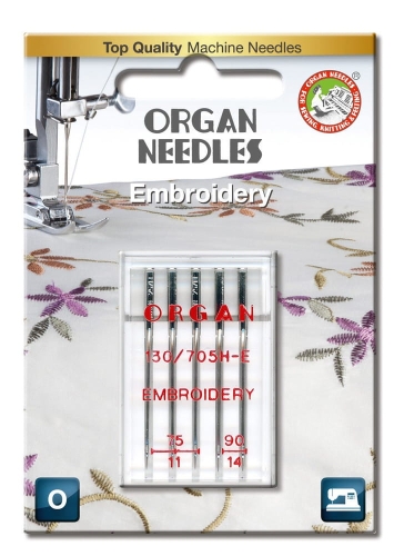Igły półpłaskie Organ 130/705H-E do haftu w blistrze, zawierające igły o rozmiarach 75 i 90. Opakowanie z przezroczystego plastiku, z widocznym logo ORGAN NEEDLES oraz oznaczeniem EMBROIDERY. Tło z delikatnym wzorem haftu.