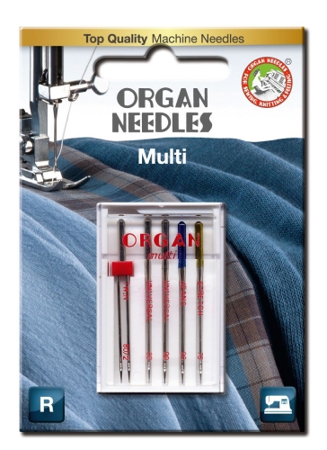 Zestaw igieł półpłaskich Organ MULTI BOX 130/705H zawiera pięć igieł: Twin, Universal, Jeans i Stretch w różnych rozmiarach. Opakowanie z przezroczystym wieczkiem ukazuje napisy w kolorze czerwonym oraz logo marki. Całość na tle materiałów.