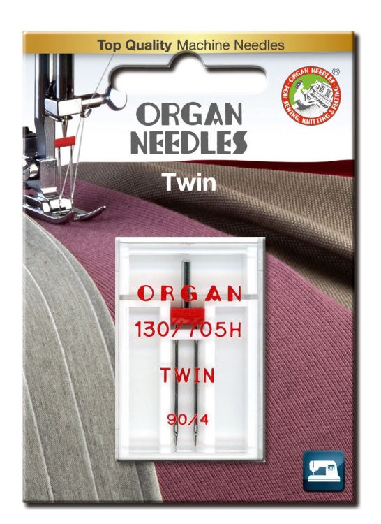 Igła podwójna półpłaska 130/705H Organ TWIN 90/4mm w przezroczystym blistrze. Widoczne dwa metalowe ostrza, oznaczenia ORGAN 130/705H i TWIN w czerwonym kolorze. Tło w odcieniach szarości i fioletu, sugerujące kontekst użytkowy.