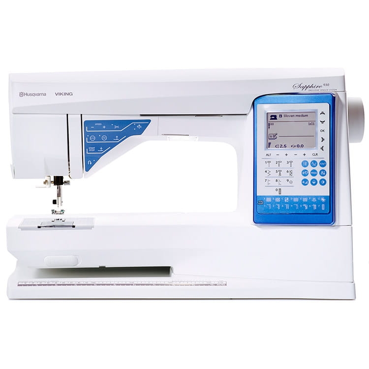 Maszyna do szycia Husqvarna Viking Sapphire 930 w białej obudowie z niebieskim panelem sterowania. Widoczny stół roboczy, igła oraz wyświetlacz LCD z programami szycia. Ujęcie frontalne, maszyna stoi na płaskiej powierzchni.