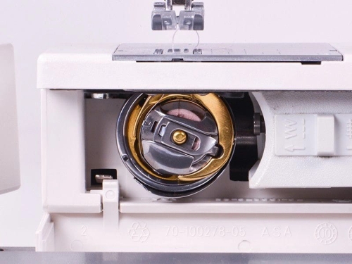 Zbliżenie na bębenek maszyny do szycia Gritzner Tipmatic 6152, ukazujący złoty element mocujący oraz różowe nici. Widoczne detale mechanizmu i obudowy w kolorze białym, z otwartą pokrywą.