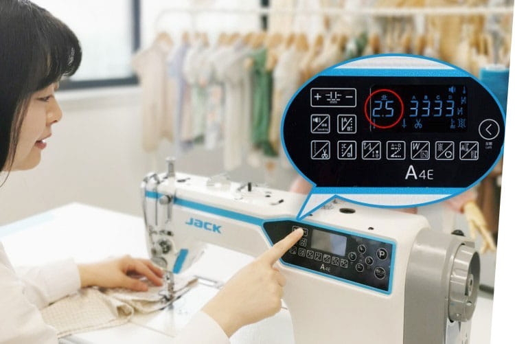 Stebnówka JACK A4C-C z widocznym panelem sterującym, na którym znajduje się cyfrowy wyświetlacz oraz ikony funkcji. Użytkownik wskazuje na przycisk. Tło z materiałami do szycia.