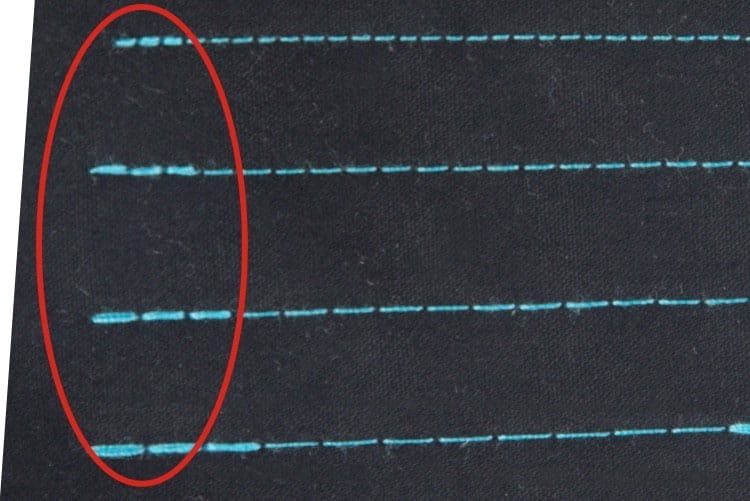 Zbliżenie na szwy wykonane stebnówką JACK A4C-C, z niebieskimi nićmi na czarnym materiale. Widoczne równe, proste linie szwów, które ilustrują precyzyjne przeszycie.