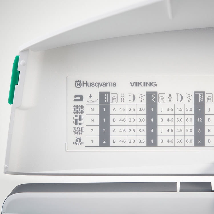 Panel maszyny do szycia Husqvarna Viking Jade 20 z wyświetlaczem funkcji i wzorów ściegów. Widoczne logo marki, tabela z oznaczeniami i parametrami ściegów, kolor biały, z elementami w szarości. Kąt ujęcia frontalny, pokazujący otwartą pokrywę.