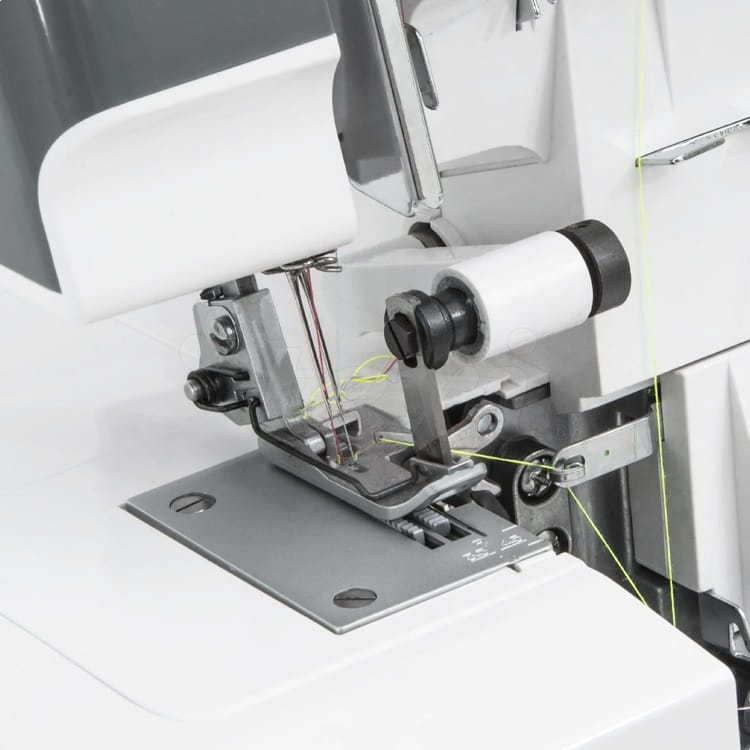 Zbliżenie na mechanizm owerloka TEXI TEGRA 4, pokazujące cztery nici, szare metalowe elementy, oraz białą szpulę. Widoczne są detale stopy oraz obszar roboczy maszyny. Tło jest neutralne, co podkreśla produkt.