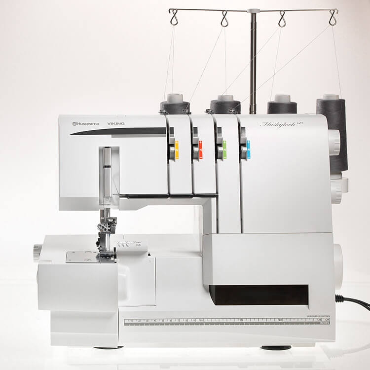 Overlock Husqvarna Viking HUSKYLOCK S21 w kolorze białym, z funkcją renderki. Widoczny z przodu, z czterema szpulkami nici. Posiada panel sterujący z czytelnymi oznaczeniami i obszerną stopką do szycia.