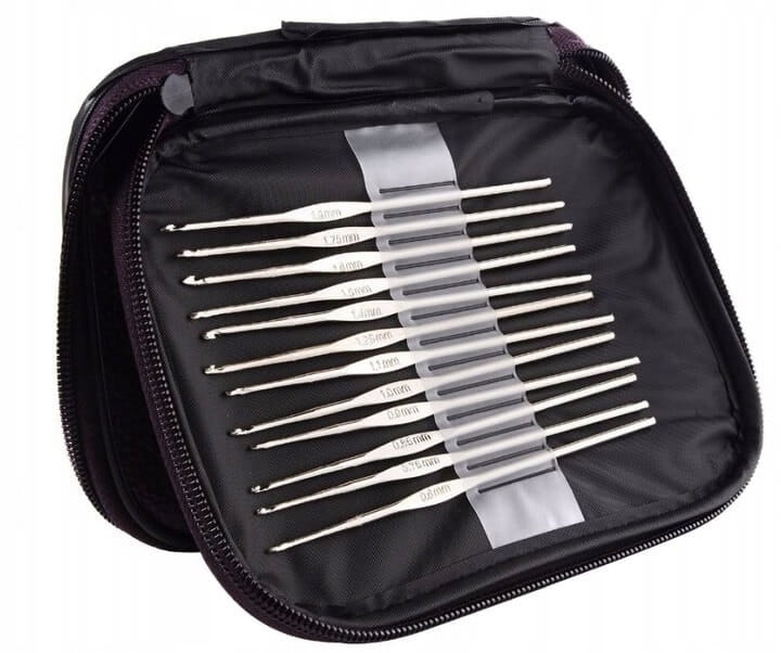 Zestaw 22 szydełek w etui, widok z góry. Szydełka metalowe o różnych rozmiarach, od 0.8 mm do 6.0 mm, ułożone w kieszonkach na czarnym tle. Etui zamykane na zamek, z uchwytem, idealne do przechowywania akcesoriów do szydełkowania.