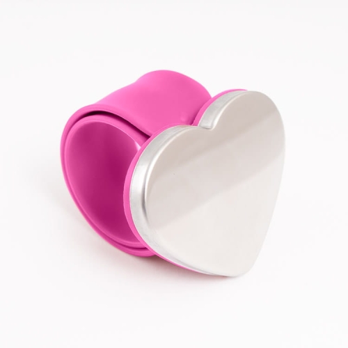 Różowa bransoletka magnetyczna TEXI LOVE PINK z sercowym, metalowym zapięciem. Wykonana z elastycznego materiału, zamontowana w pozycji stojącej, idealna do przechowywania igieł i szpilek. Proste tło podkreśla kolor i kształt produktu.