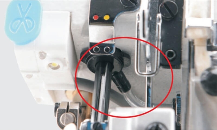 Zbliżenie na mechanizm owerloka Jack C5F-4, ukazujące elementy sterujące, w tym dwa otwory oraz przycisk w kolorze niebieskim. Widoczne są także metalowe mocowania oraz przewód, co wskazuje na zaawansowaną konstrukcję maszyny.