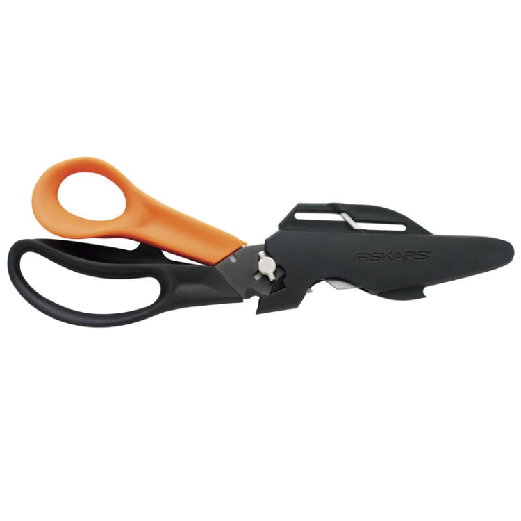 Nożyczki wielofunkcyjne Fiskars Cuts+More 23 cm w kolorze czarnym z pomarańczowymi uchwytami. Produkt z ostrzami do cięcia, z funkcją otwierania butelek, stojący w pozycji zamkniętej, z widocznym logo Fiskars.