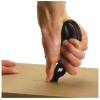 Nożyczki wielofunkcyjne Fiskars Cuts+More 1000809 w czarnej kolorystyce, trzymane w dłoni, używane do cięcia kartonu. Widoczny uchwyt o ergonomicznym kształcie, dedykowane do precyzyjnego cięcia. Produkt w akcji, z bliska na detal cięcia.
