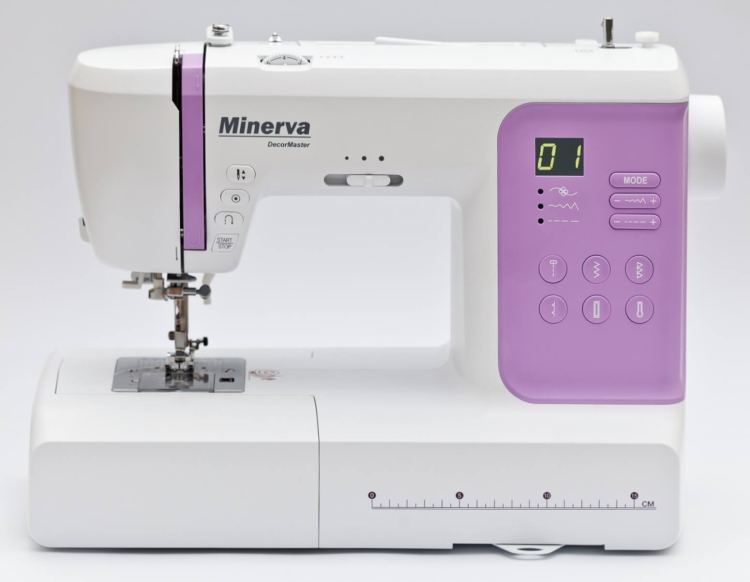 Maszyna do szycia Minerva DecorMaster w kolorze białym i fioletowym, z wyświetlaczem LCD, przyciskami do wyboru ściegów oraz funkcją start/stop. Widoczna stopka i metalowa płytka. Ułożona na płaskiej powierzchni, z jasnym tłem.