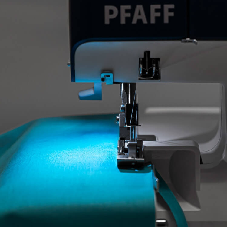 Owerlok PFAFF ADMIRE 1000, 4-nitkowy, widok z boku na igłę i stopkę, z jasnoniebieskim materiałem w tle. Maszyna ma logo PFAFF, a oświetlenie podkreśla fakturę tkaniny.