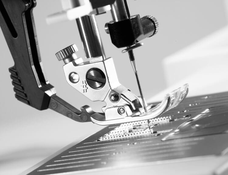Stopka maszyny do szycia PFAFF QUILT AMBITION 635 z podwójnym transportem, zbliżenie na igłę oraz mechanizm, metalowa konstrukcja, widoczna płytka ściegowa, detale dostosowania.