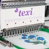 Hafciarka TEXI 1501 TS PREMIUM, 15-igłowa, z widocznym logo texi. Zbliżenie na igły i haft z niebieskimi kwiatami na białym tle, umieszczonym w zielonym tamborku. Maszyna w pozycji roboczej, gotowa do szycia.