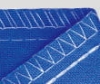 Fragment niebieskiego materiału z wykończeniem w białych szwach, prezentujący szczegóły 5-nitkowego ściegu owerloka SIRUBA 757L-516M3-55/DKLU. Widoczny kąt szycia oraz struktura tkaniny.