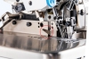 Zbliżenie na mechanizm owerloku JACK C2-3-02/233, ukazujące nóż tnący w pozycji roboczej. Elementy metalowe o matowym wykończeniu, widoczne przyciski i śruby, srebrna powierzchnia robocza. Tło jasne, neutralne.
