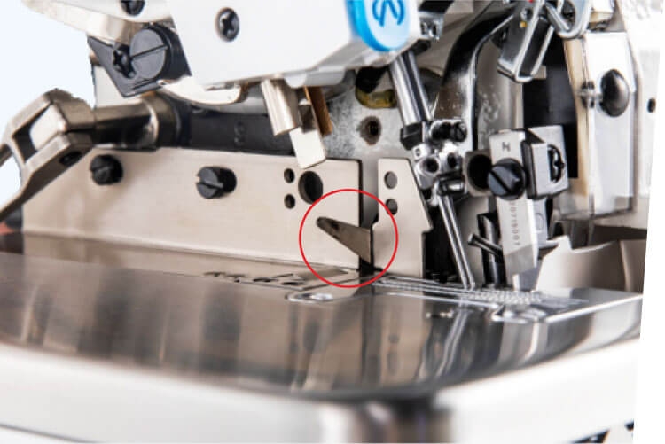 Zbliżenie na mechanizm owerloku JACK C2-3-02/233, ukazujące nóż tnący w pozycji roboczej. Elementy metalowe o matowym wykończeniu, widoczne przyciski i śruby, srebrna powierzchnia robocza. Tło jasne, neutralne.