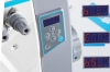 Panel sterujący owerloka JACK C2-5-03/233 z wyświetlaczem LCD, pokazującym wartości numeryczne. Widać przyciski do regulacji oraz oznaczenie modelu C2. Szare elementy obudowy i niebieskie akcenty.