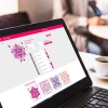 Ekran laptopa z interfejsem maszyno-hafciarki Husqvarna Viking DESIGNER EPIC 2, wyświetlający projekt Victorian Floral Ornament oraz powiązane wzory. Tło rozmyte, widać filiżankę z napojem.
