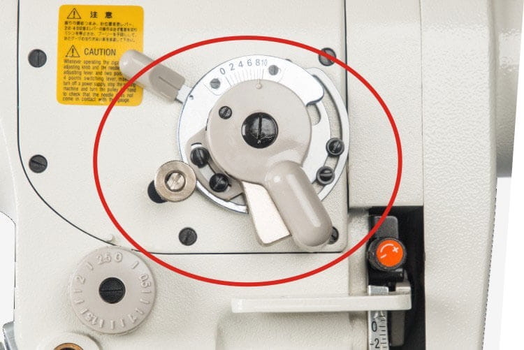 Zbliżenie na panel sterujący maszyny do szycia Zygzak JACK JK-T2284B-4E. Widoczne pokrętło ustawienia, przycisk włączania oraz oznaczenia na tarczy. Tło białe, produkt w pozycji pionowej.