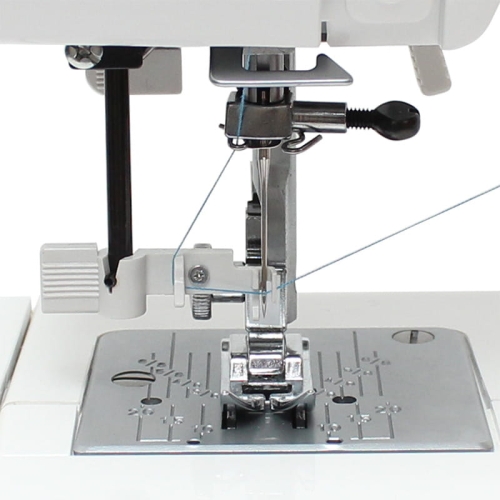 Nawlekacz igły do maszyn JUNO J15R, E1019, E1030, Janome 1522 i Elna 220, 240, widoczny z bliska, umieszczony przy igle maszyny. Metalowa stopka i szara płytka z oznaczeniami, igła z nitką, wyraźnie widoczna w centralnej części.