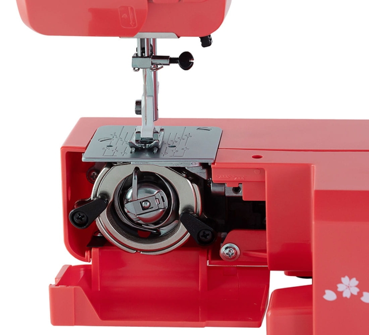 Maszyna do szycia Janome JUNO E1015 w kolorze czerwonym z widocznym mechanizmem bębenka i igłą. Kąt ujęcia z przodu, ukazujący szczegóły podzespołów oraz metalową płytkę. Idealna do szycia w domowych projektach.