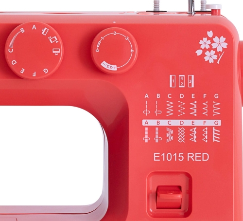 Maszyna do szycia Janome JUNO E1015 w kolorze czerwonym, z pokrętłami do regulacji oraz różnymi wzorami ściegów widocznymi na obudowie. Logo z kwiatami na obudowie, z oknem do szycia z przodu. Idealna dla początkujących i hobbystów.