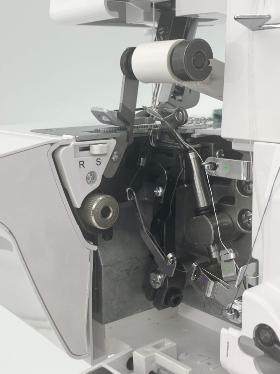 Owerlok Minerva ML3314 z widocznym mechanizmem, w tym rolką z białą nicią, metalowymi elementami i dźwigniami. Ujęcie z boku, ukazujące wnętrze maszyny do szycia, na jasnym tle.