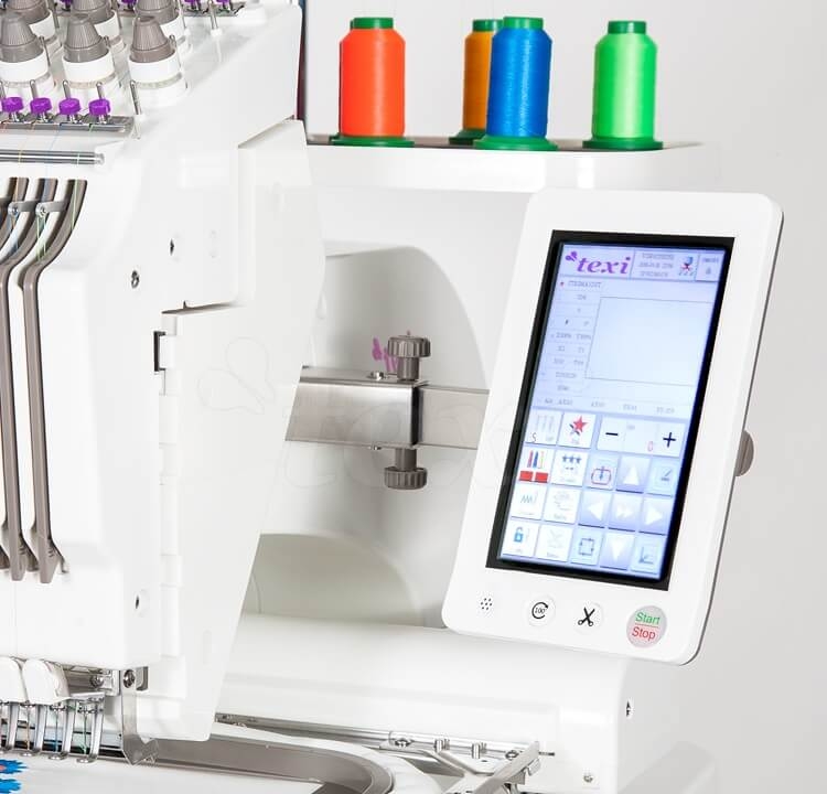 Hafciarka TEXI IRIS 10, przemysłowa, 10-igłowa. Widok z boku, z wyświetlaczem dotykowym, obok kolorowe szpulki nici: zielona, niebieska, pomarańczowa i czerwona. Widoczne prowadnice nici oraz igły. Tło jednolite, jasne.