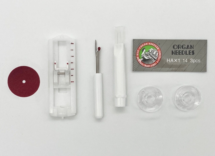 Zestaw akcesoriów do maszyny do szycia Minerva MAX 30, w tym białe prowadnice, czerwony okrągły znacznik, narzędzie do wypruwania, opakowanie z igłami ORGAN NEEDLES HA x1 14 (3 sztuki) oraz dwa przezroczyste szpulki.