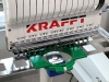 Hafciarka KRAFFT KF-CT1501H, jednogłowicowa, 15-igłowa, z widoczną głowicą z logo KRAFFT. Na pierwszym planie znajduje się zielony uchwyt materiału oraz metalowa płyta z kwadratowymi otworami. Ujęcie z przodu, ukazujące detale mechanizmu.