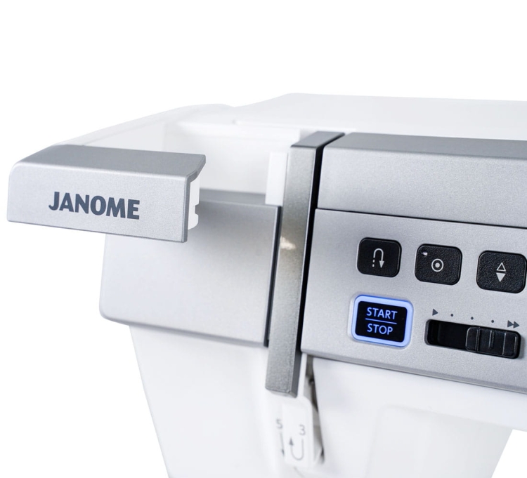 Maszyna do szycia Janome MC9480QCP Professional w kolorze białym z metalowymi akcentami. Widoczne przyciski sterujące w tym niebieski przycisk START STOP. Logo JANOME umieszczone na bocznej części maszyny. Produkt z bliska, ukazujący szczegóły panelu