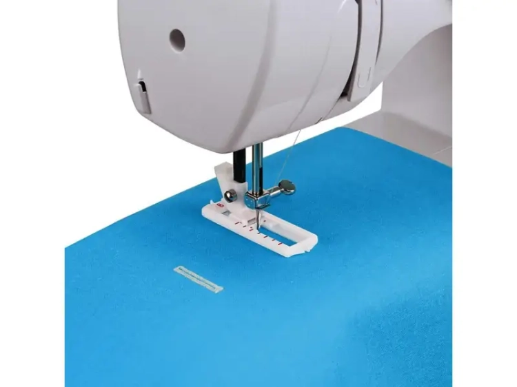 Maszyna do szycia BERNETTE Sew&Go 3 w białej obudowie z widocznym mechanizmem szyjącym i stopką na niebieskim materiale. Widoczne ustawienia długości ściegu oraz igła gotowa do pracy.