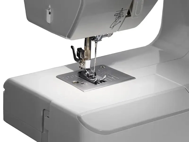 Maszyna do szycia BERNETTE Sew&Go 5, widok z góry na igłę i stopkę, metalowa płyta z oznaczeniami ściegów, prostokątna, biały korpus, mechaniczna konstrukcja, 23 dostępne ściegi.