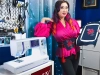 Maszyno-hafciarka BERNETTE B79 SE Yaya Han w kolorze białym z fioletowymi akcentami, z panelem sterującym. Obok osoba trzyma haftowany materiał w ramce, w tle przybory krawieckie na ścianie.