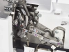 Zbliżenie na wnętrze owerloka BERNETTE B44 FUNLOCK, ukazujące mechanizm z metalowymi elementami, dźwigniami i kolorowymi oznaczeniami. Widoczne śruby oraz części robocze maszyny, z jasnym tłem, co podkreśla detale konstrukcyjne.