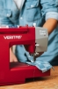 Maszyna do szycia Veritas Power Stitch 17 w kolorze czerwonym, z szarym panelem, prezentująca mechanizm szycia na niebieskiej tkaninie w kratę. Ujęcie z boku, z widocznym wątkiem i igłą, z ręką operatora trzymającą materiał.