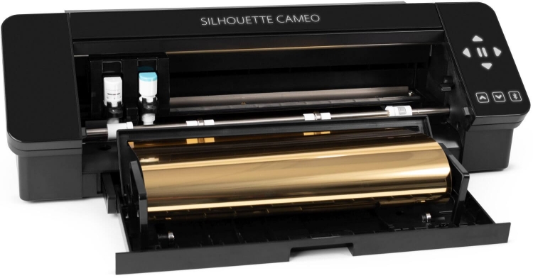 Ploter tnący Silhouette Cameo 4 w kolorze czarnym, z otwartą komorą, ukazuje złotą rolkę materiału. Widoczne elementy sterujące oraz pojemniki na tusz. Kąt ujęcia z przodu, eksponujący detale urządzenia i jego funkcje.
