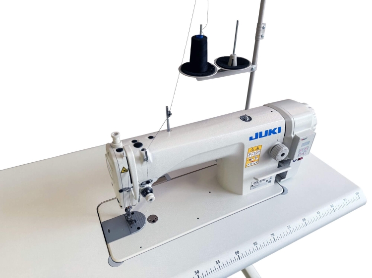 Stebnówka JUKI DDL-8700H jednoigłowa do ciężkiego szycia, z silnikiem Direct Drive. Widok z boku, z widocznym białym blatem, uchwytem na szpulki oraz elementami sterującymi na obudowie.